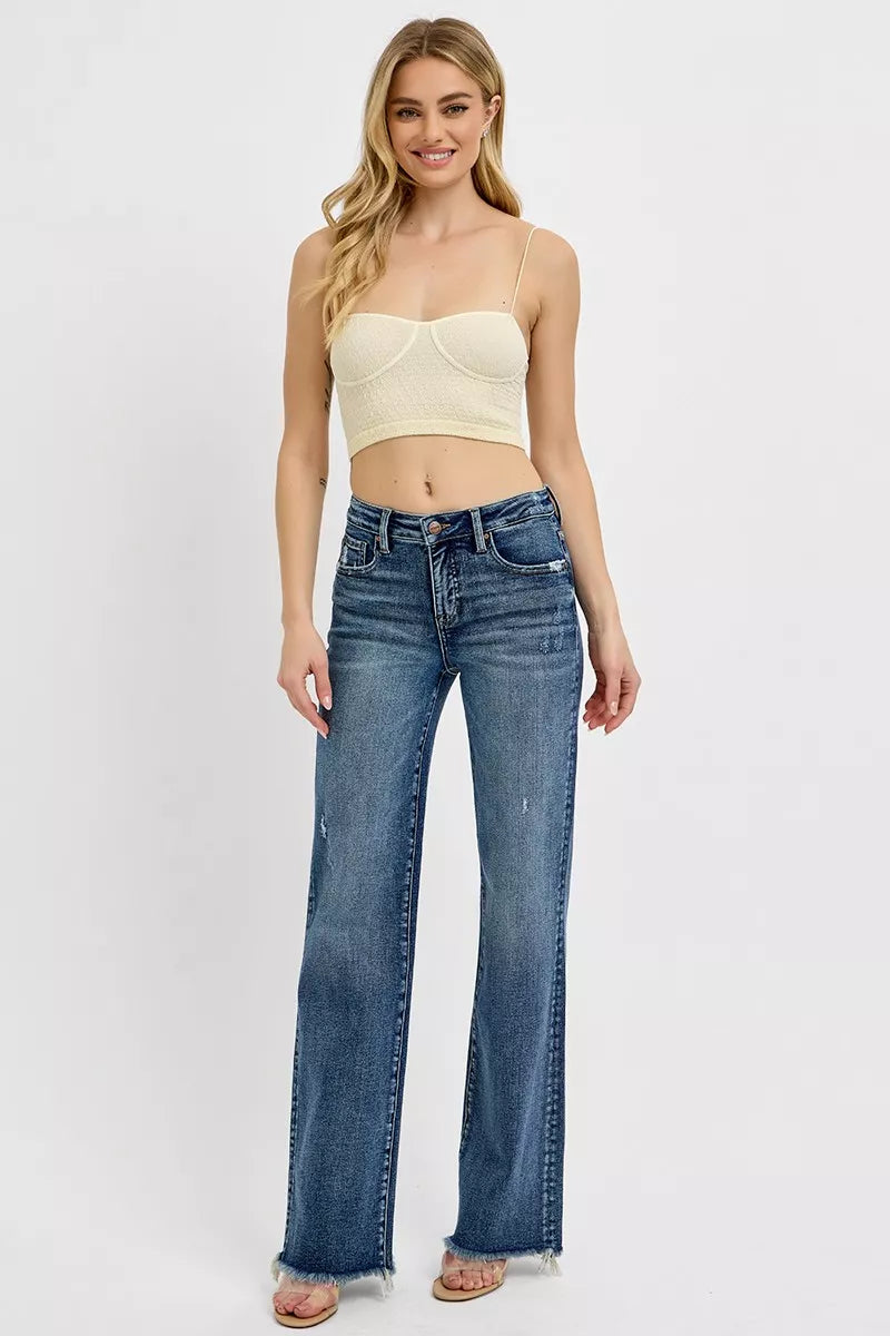 Woman wearing a beige crop top and blue jeans on a white background