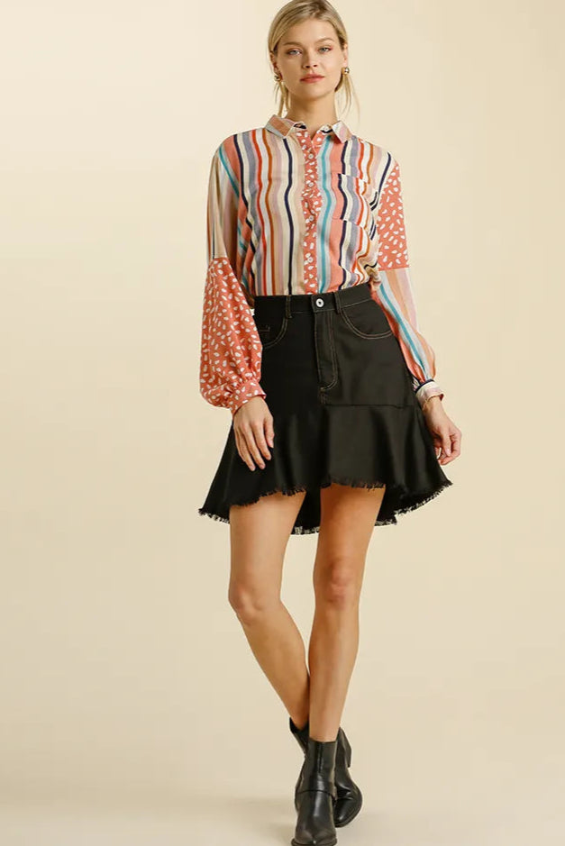 Woman wearing a colorful striped shirt and black skirt on a beige background
