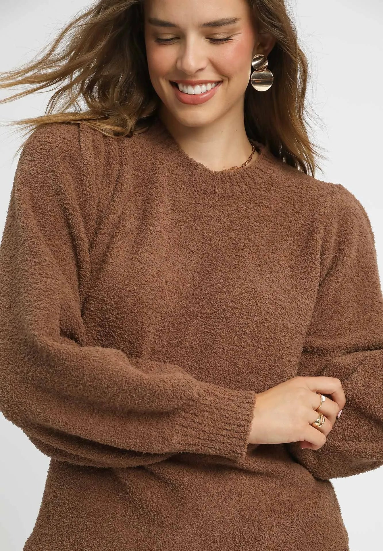 Woman wearing a brown sweater with a plain background