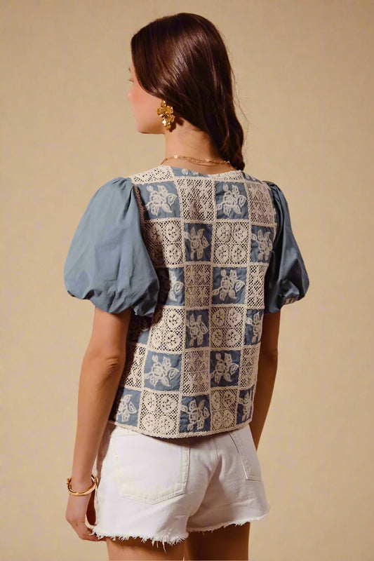Woman wearing a patterned top with blue sleeves and beige background