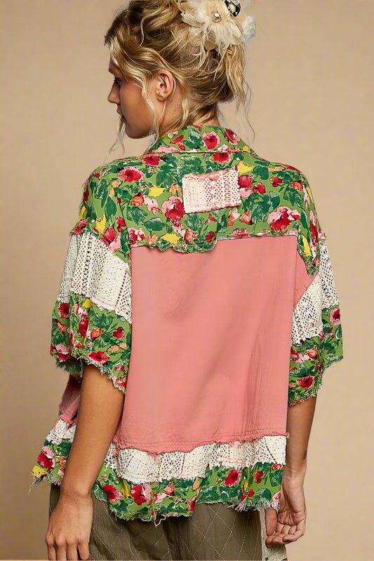 Person wearing a floral and pink layered shirt against a gray background