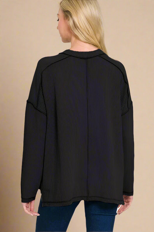Black ribbed sweater worn by a person on a beige background