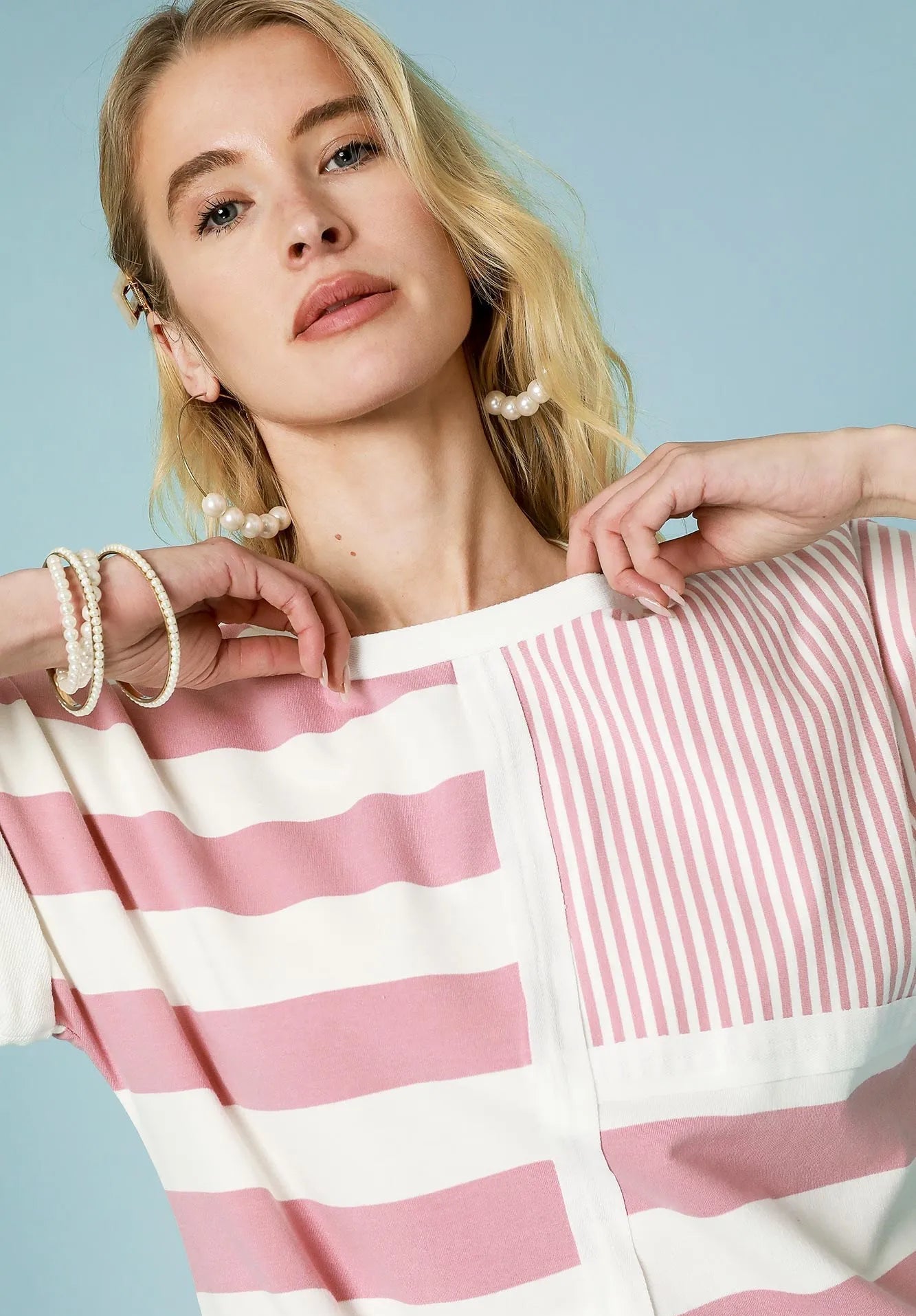 Woman wearing a pink and white striped romper against a light blue background