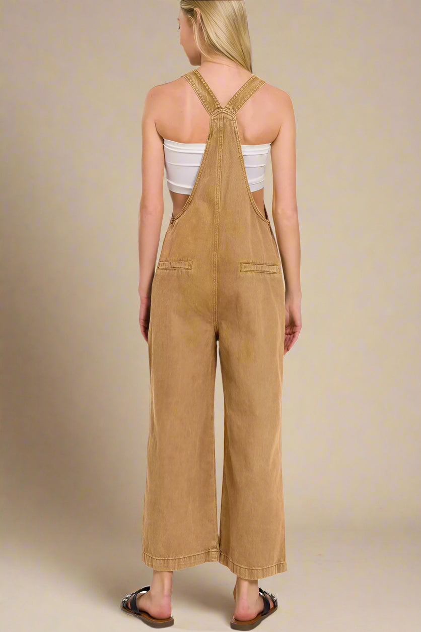 Woman wearing a deep camel colored overalls on a white background