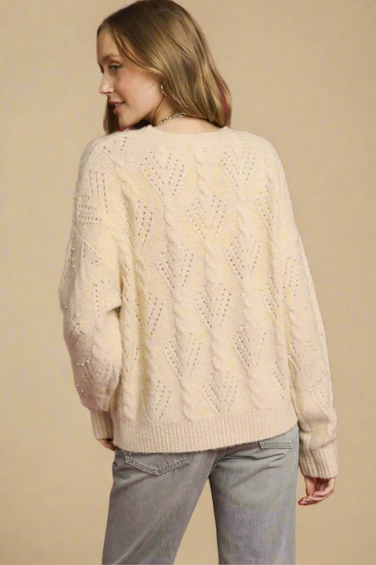 Woman wearing a cream sweater against a red background