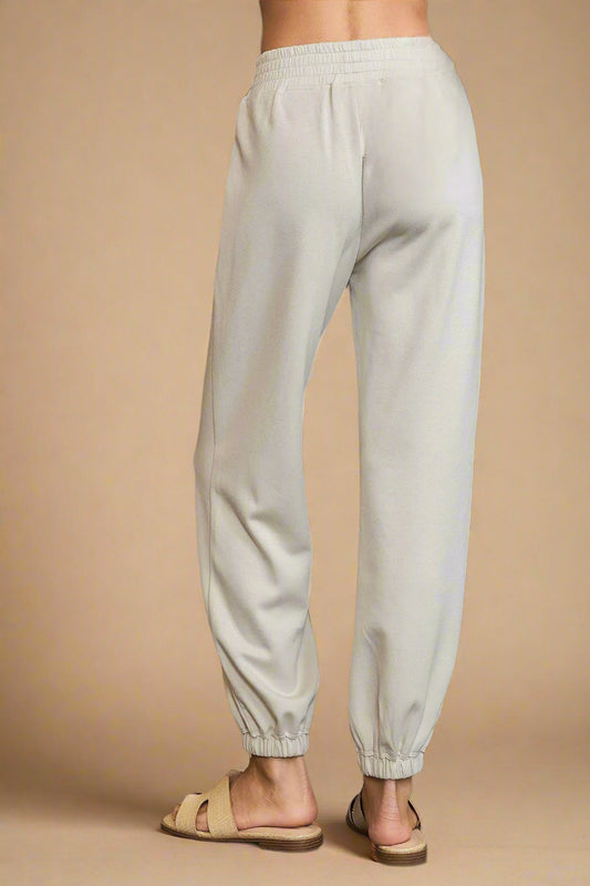 Light gray sweatpants worn by a person on a gray background