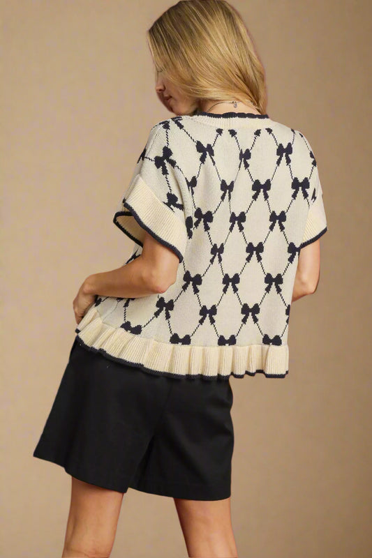 Woman wearing a cream cardigan with black bow pattern on a red background