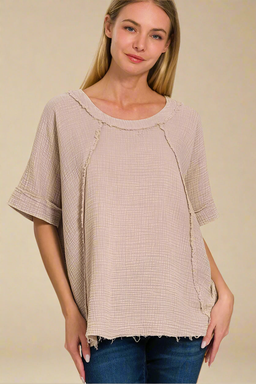 Woman wearing a beige textured top with a plain background