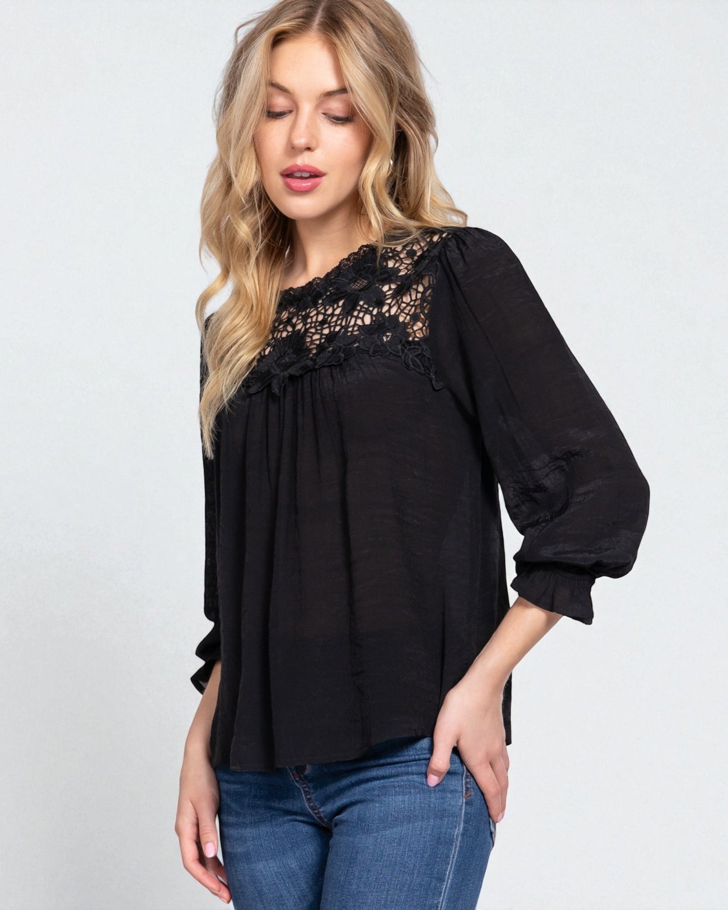 Woman wearing a black blouse with lace details on a white background