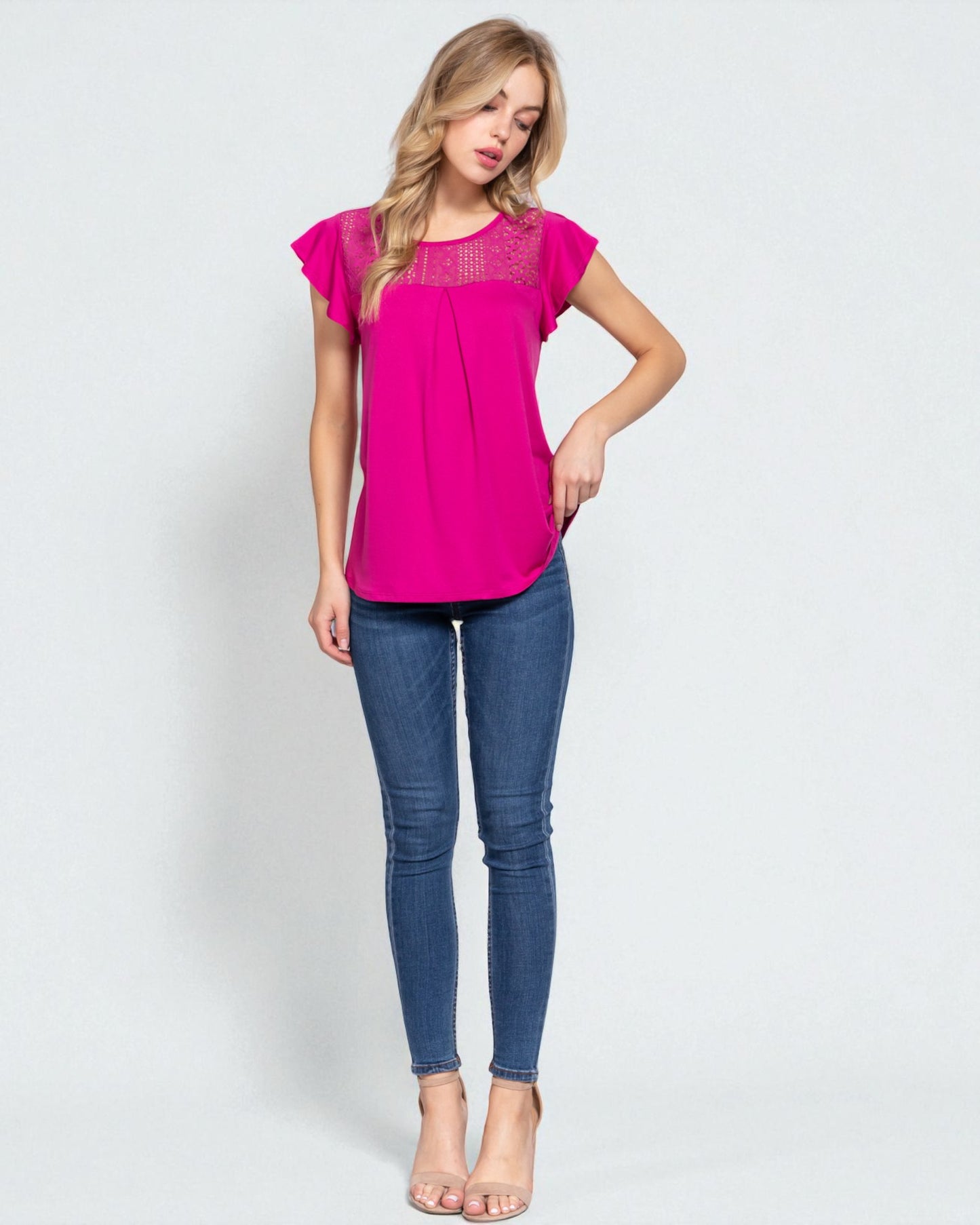 Woman wearing a pink top and blue jeans on a white background