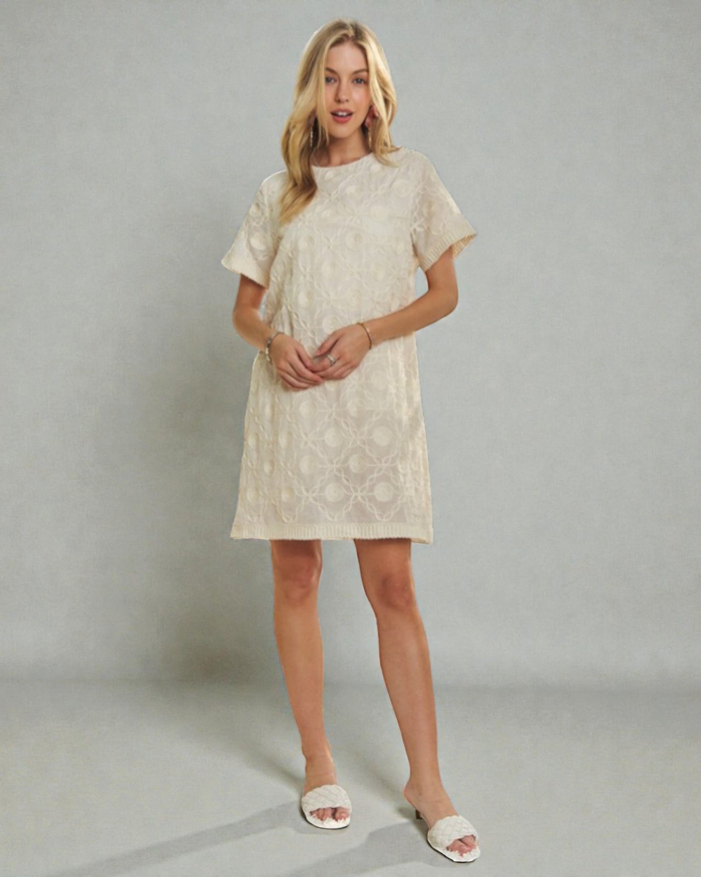 Woman wearing a white lace dress against a plain background