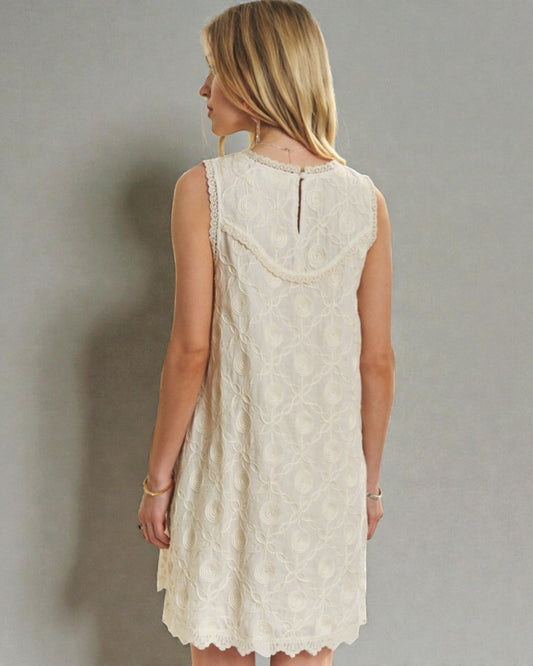 Woman wearing a white lace dress against a plain background