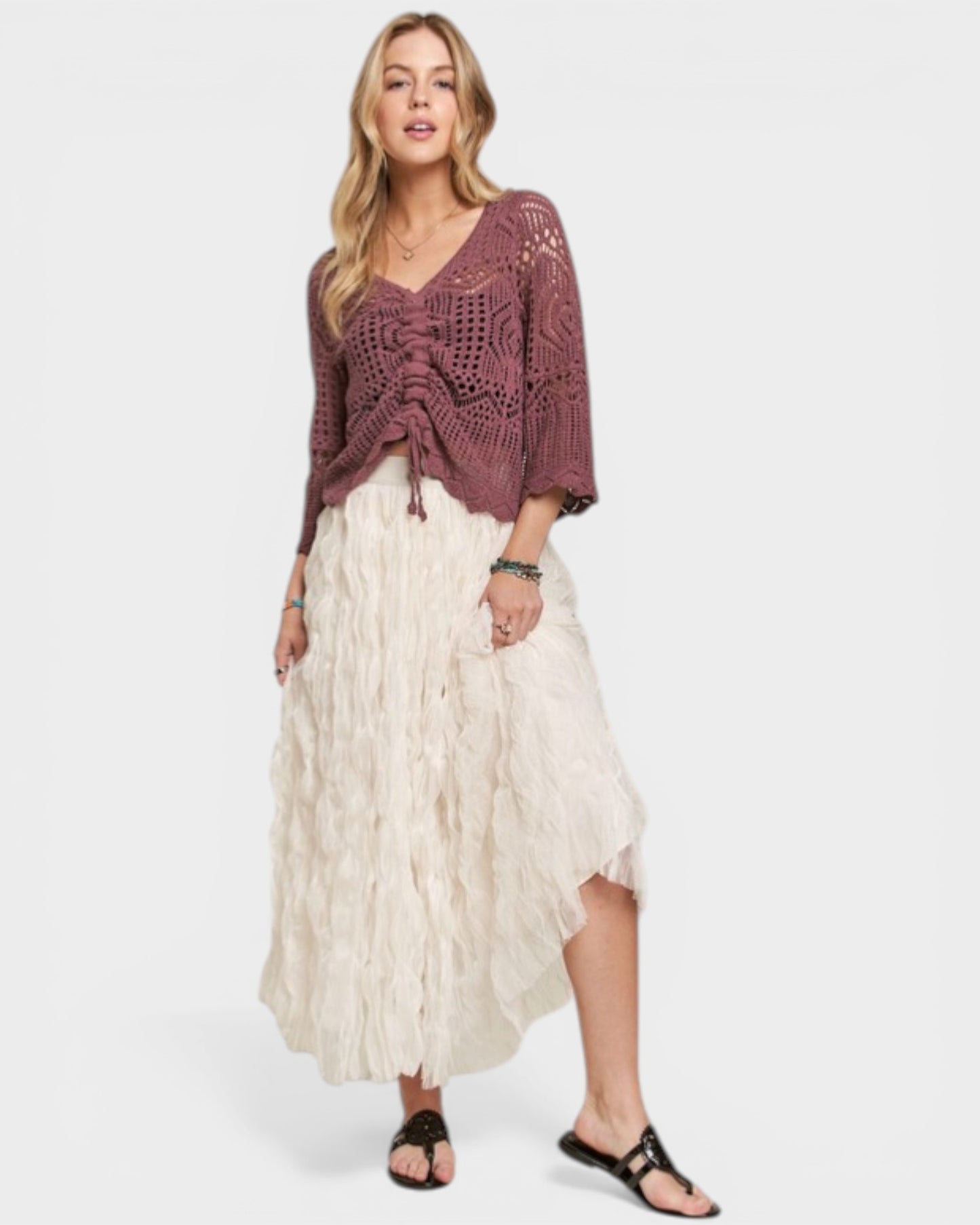 Woman wearing a maroon crochet top and white skirt on a white background