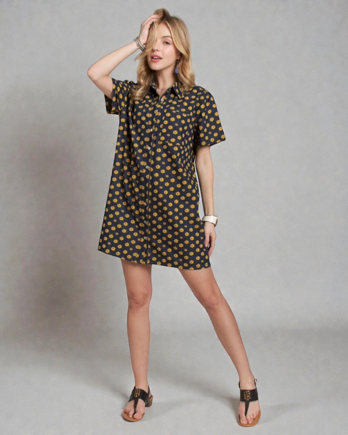 Woman wearing a black dress with gold polka dots on a gray background