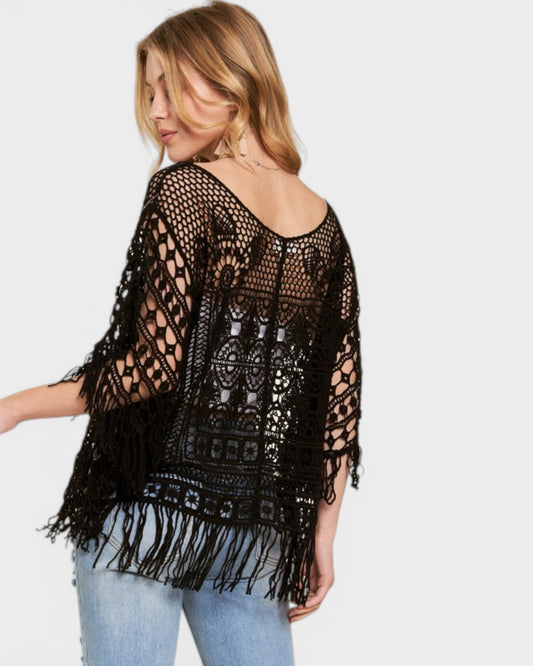 Woman wearing a black crochet top with fringe on a white background