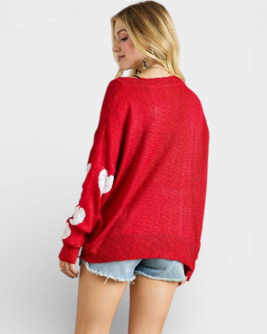 Person wearing a red sweater with white patterns on a plain background