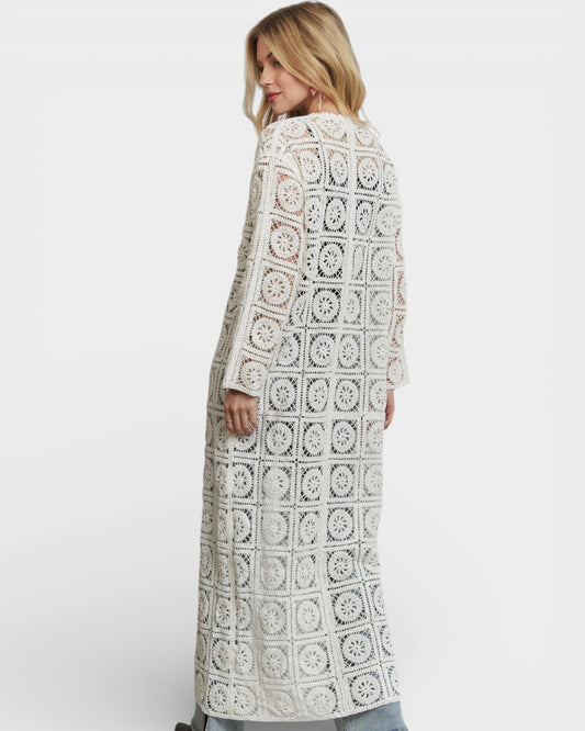 Woman wearing a long, patterned coat against a white background