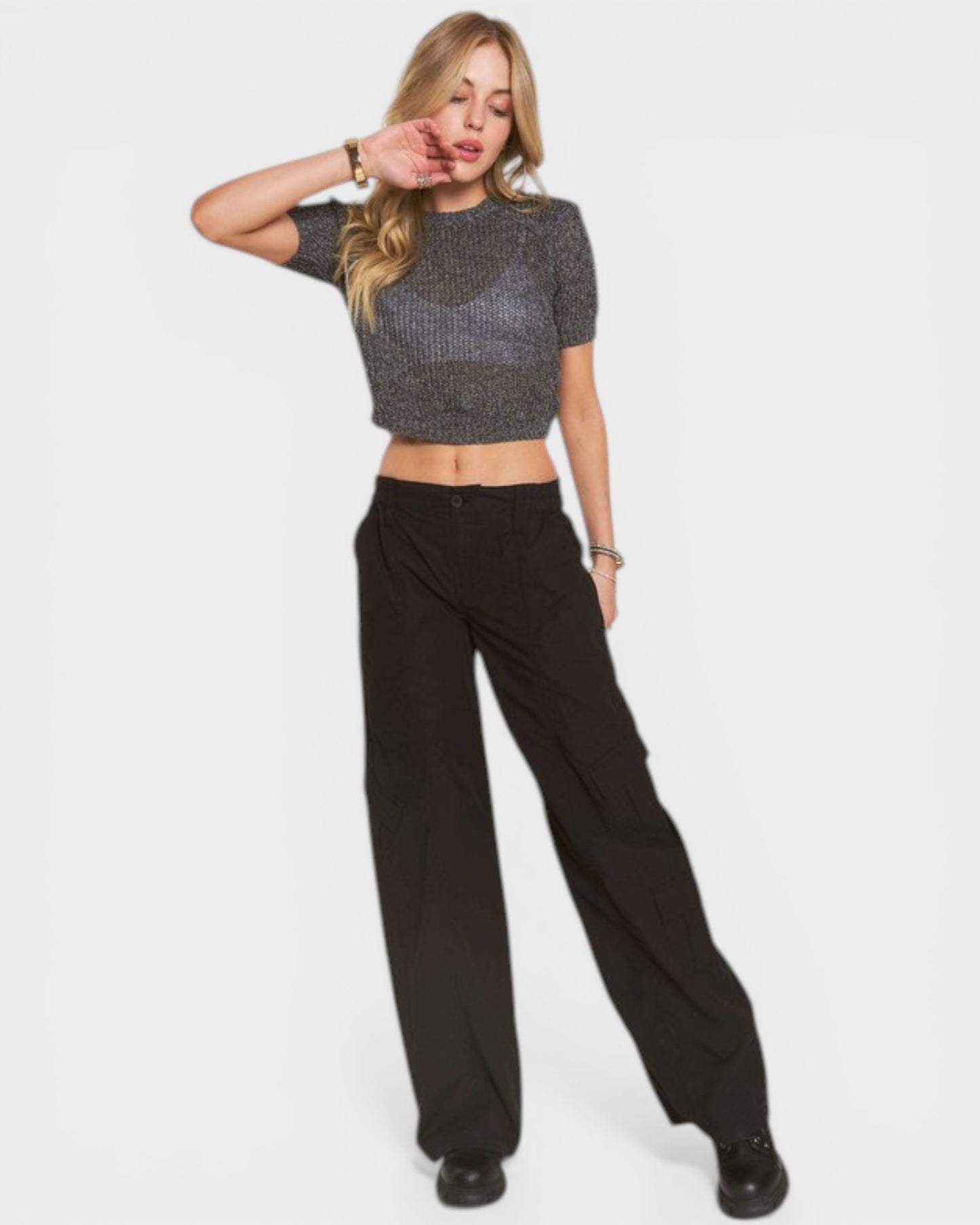Woman wearing a gray cropped top and black high-waisted pants on a white background