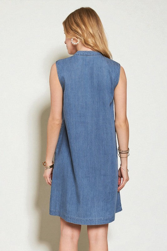 Woman wearing a blue denim dress against a plain background