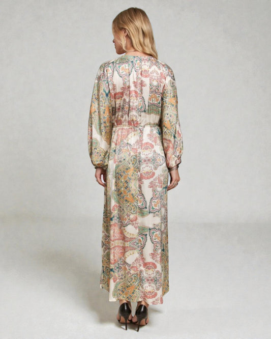 Woman wearing a floral dress with long sleeves on a plain background