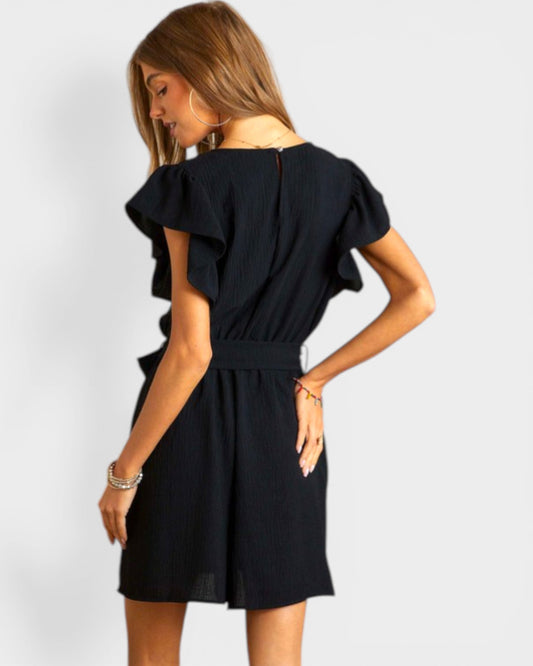 Woman wearing a black dress with ruffled sleeves on a white background