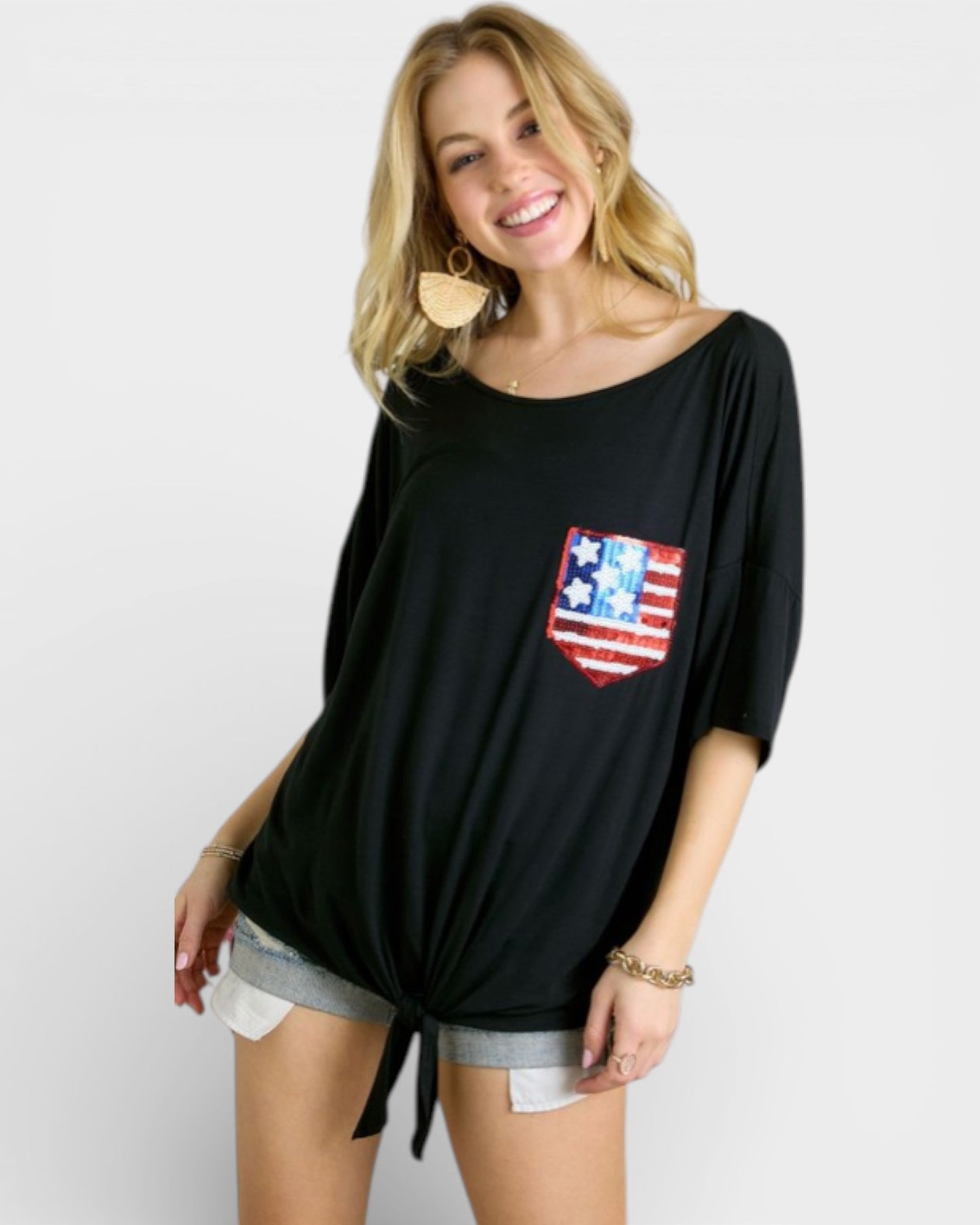 Woman wearing a black oversized shirt with a red pocket featuring a white star design on a plain background