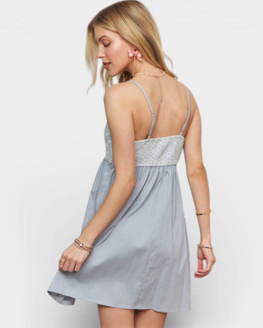 Woman wearing a light blue dress with a silver embellished top on a white background