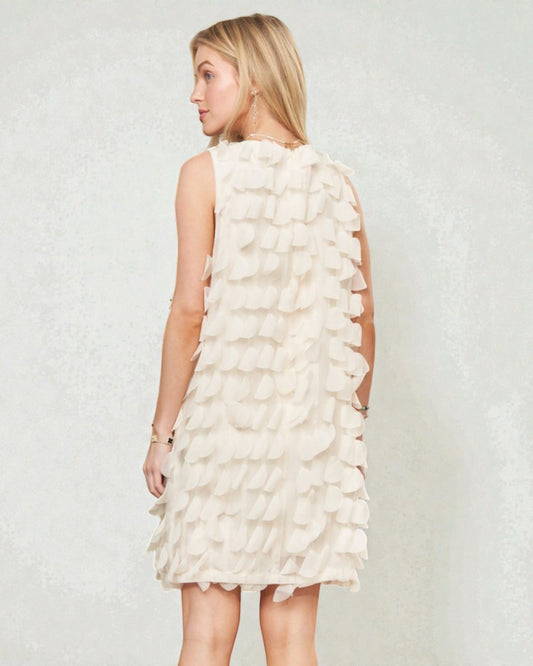 Woman wearing a white ruffled dress against a plain background