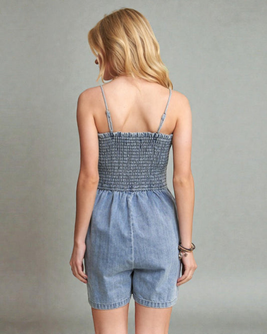 Woman wearing a denim romper against a plain background