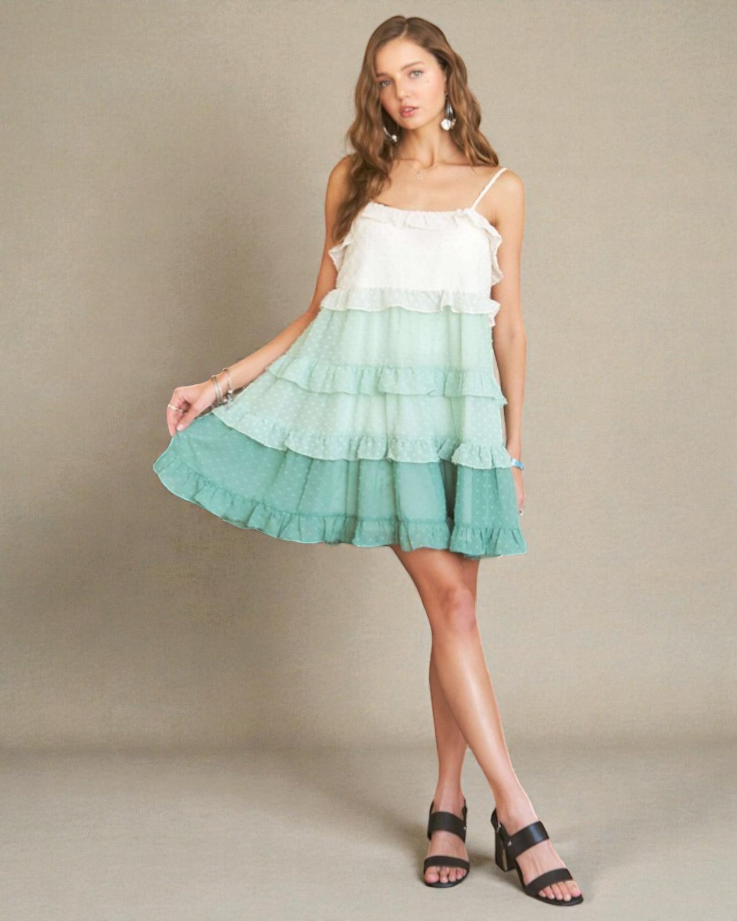 Woman wearing a white and green tiered dress on a beige background