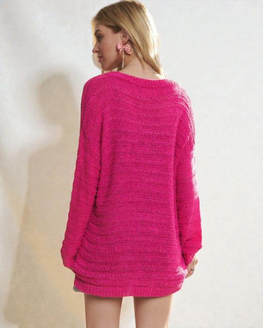 Person wearing a pink knitted sweater against a plain background
