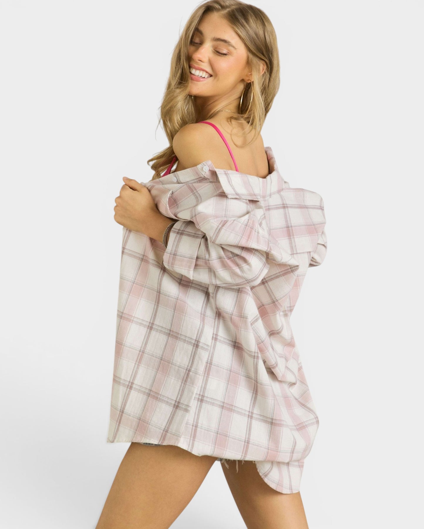 Woman holding a plaid shirt over her shoulder against a white background