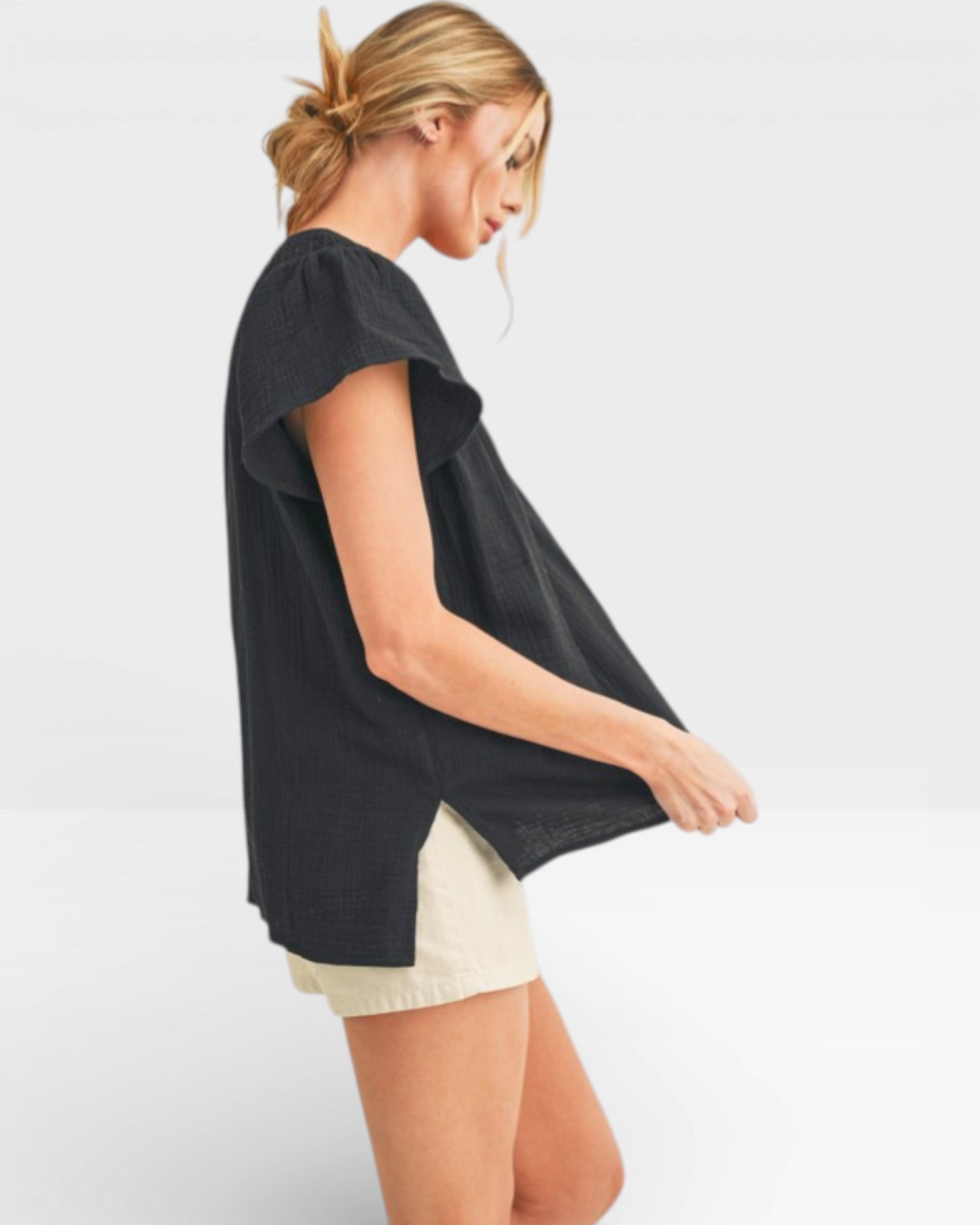 Woman wearing a black top and white shorts on a light gray background