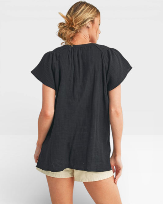 Woman wearing a black top and beige shorts on a white background