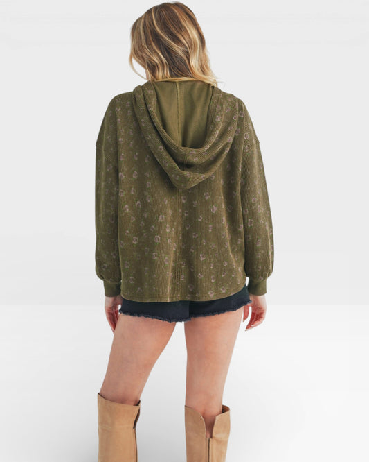 Person wearing a green hoodie with a white pattern on a white background