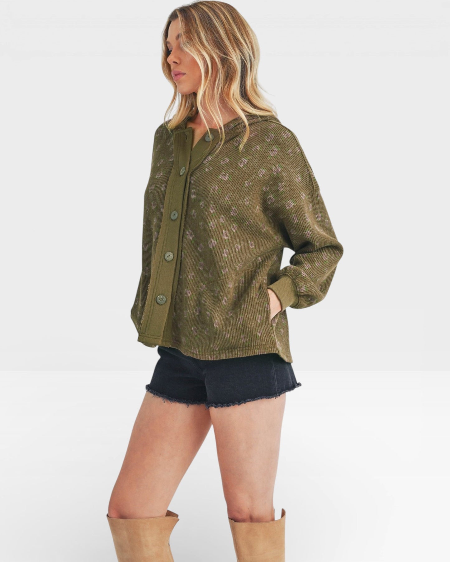 Woman wearing a green patterned shirt and black shorts on a white background