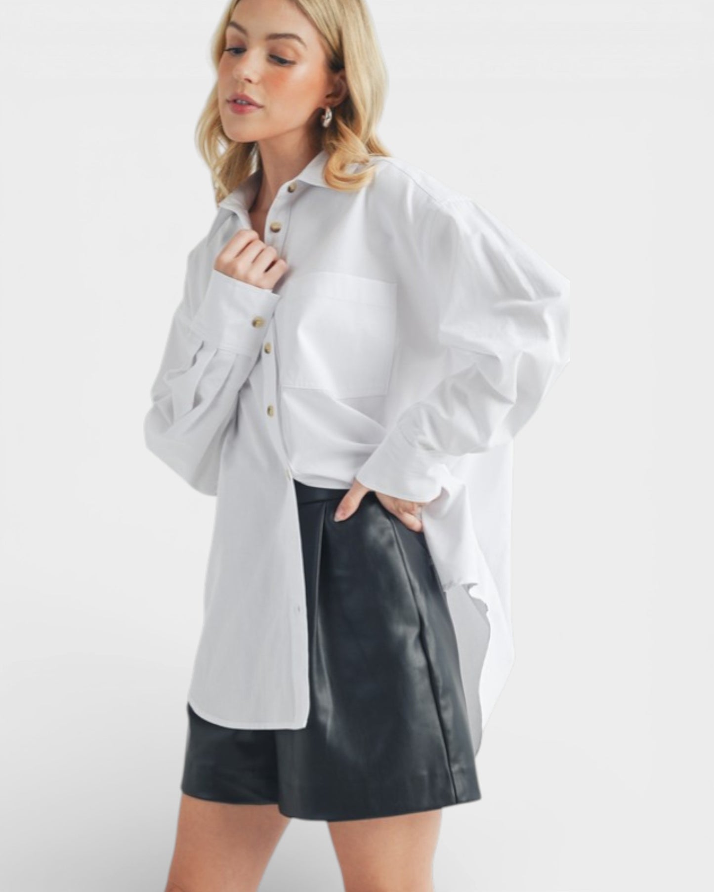 Woman wearing a white shirt over a gray shirt with a black leather skirt on a white background