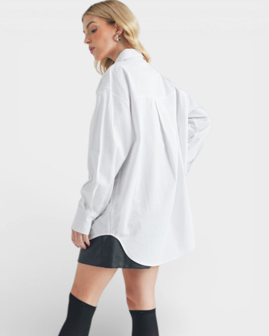 Person wearing a white oversized shirt and black shorts on a plain background