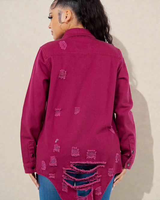 Person wearing a pink distressed denim jacket against a beige wall