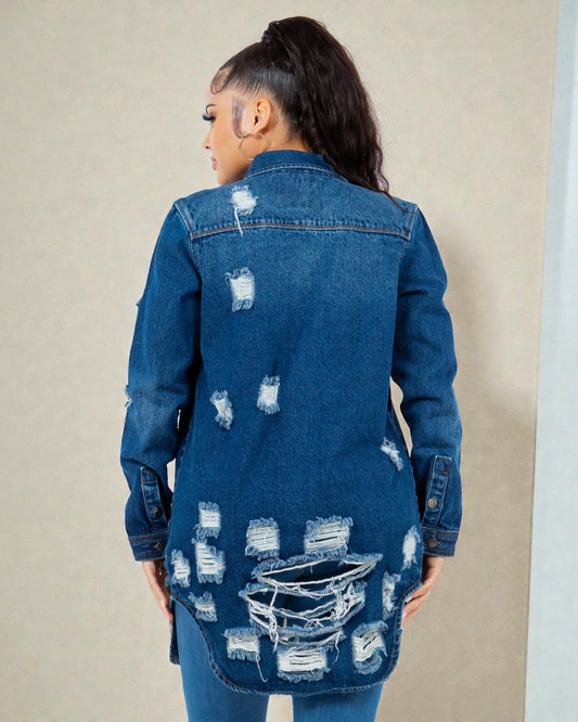 Person wearing a blue distressed denim jacket against a beige background