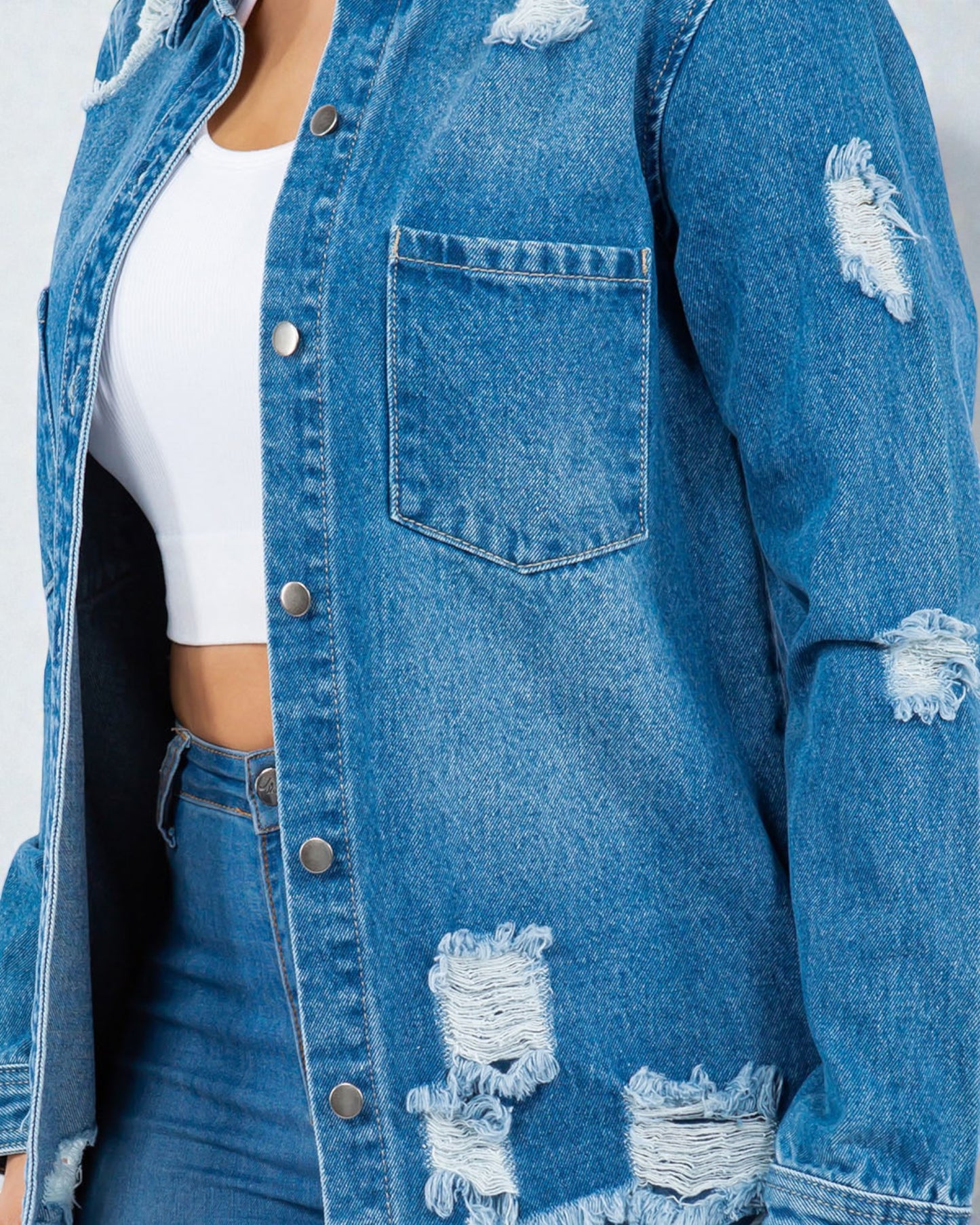 Ripped blue denim jacket worn by a person on a white background