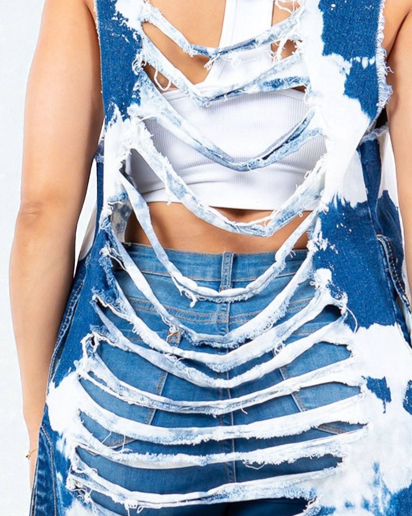 Person wearing a blue denim dress with white paint splashes and a white crop top.