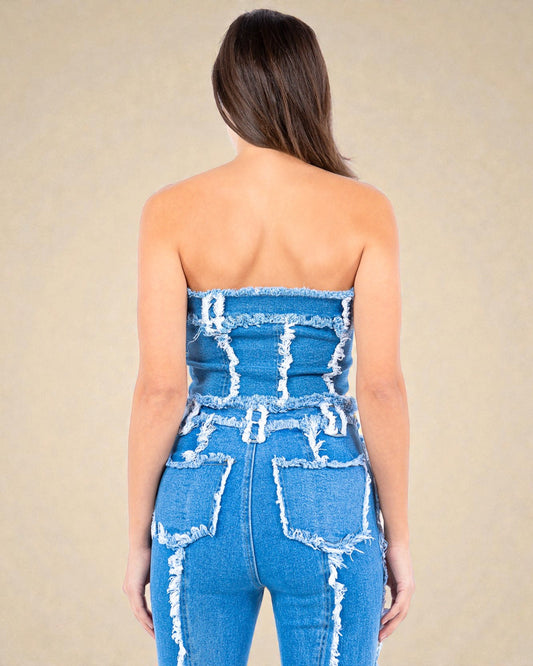 Woman wearing a strapless denim jumpsuit with a beige background