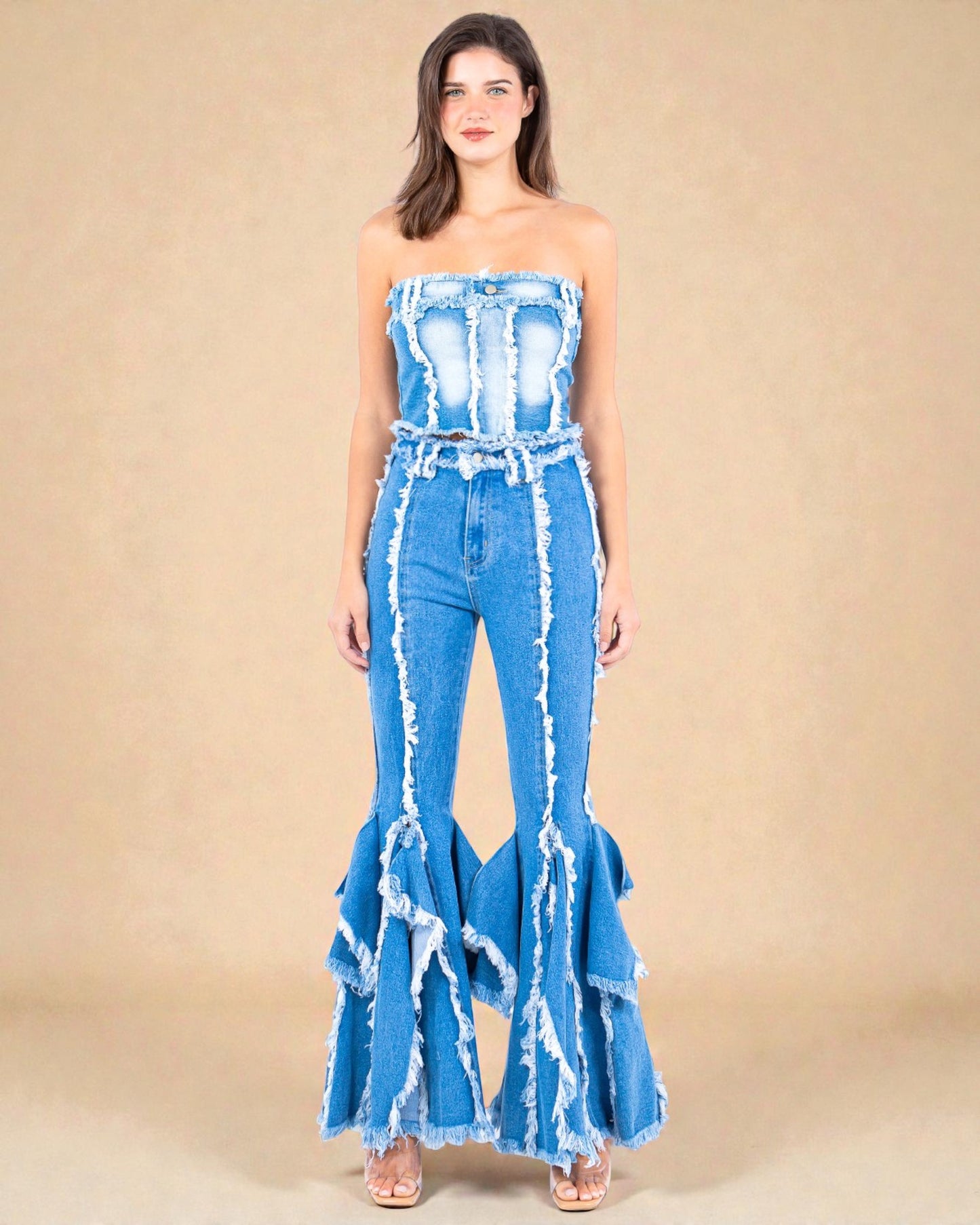 Woman wearing a blue denim jumpsuit with ruffled details on a beige background