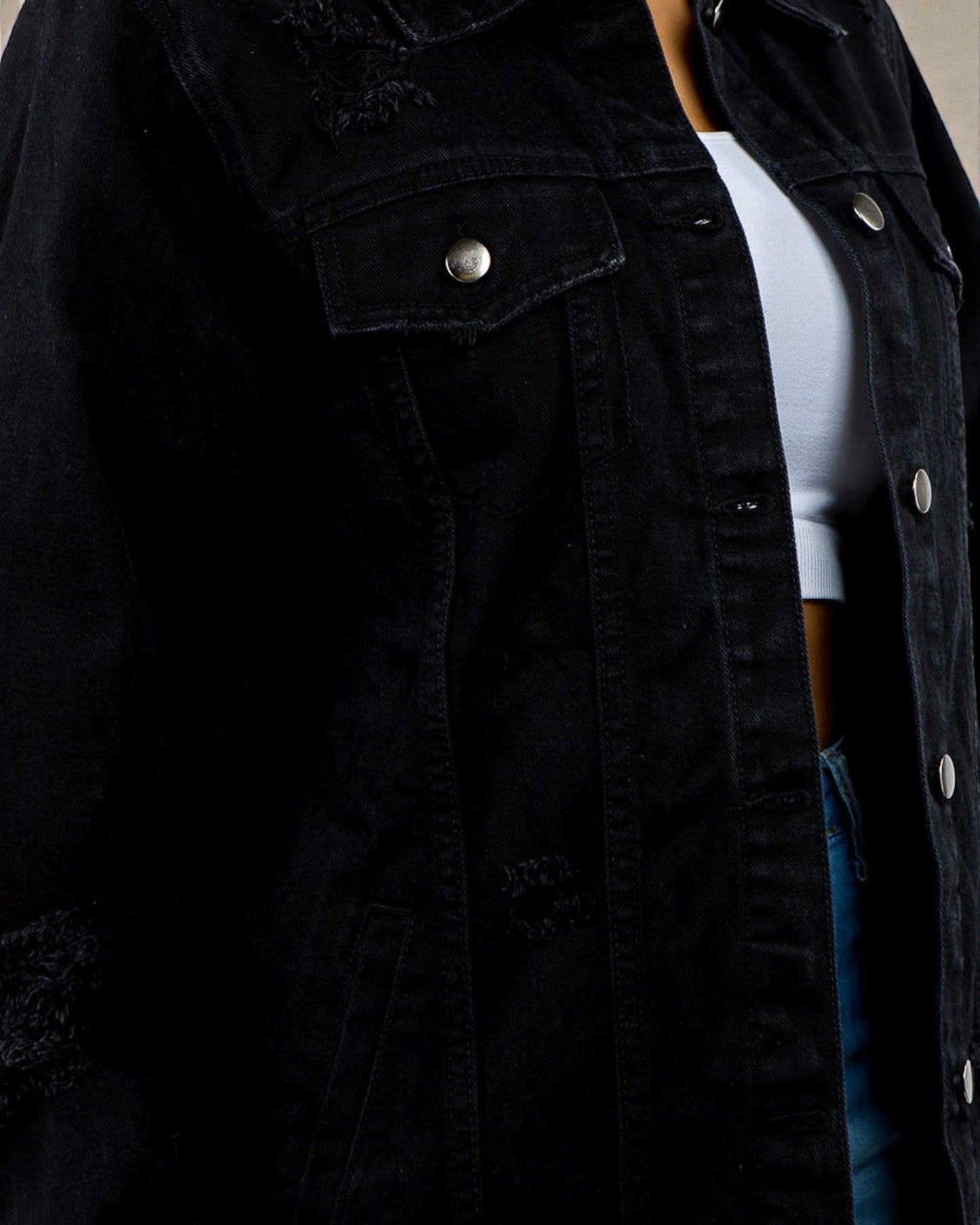 Black denim jacket with a person wearing it, partially visible
