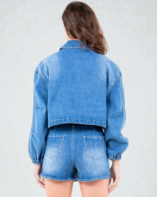 Person wearing a blue denim jacket and shorts on a plain background