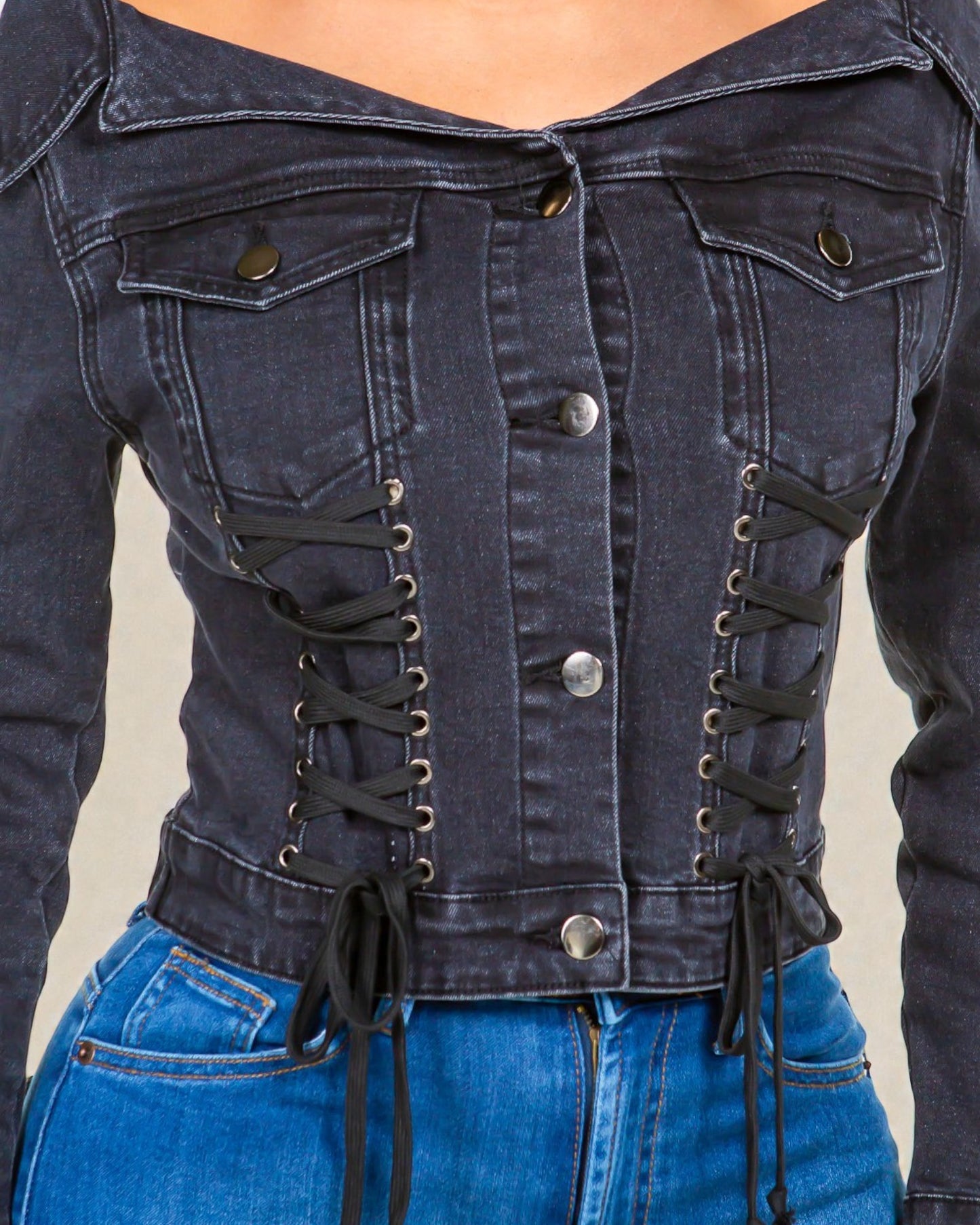 Denim jacket with lace-up front and button details on a neutral background