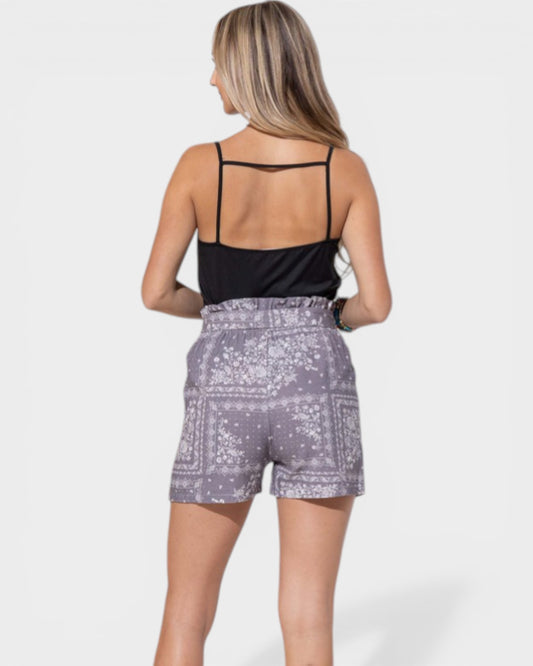 Woman wearing a black top and patterned shorts on a white background