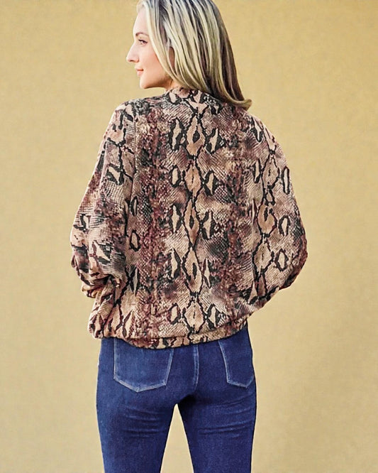 Person wearing a snake print blouse and blue jeans against a beige background