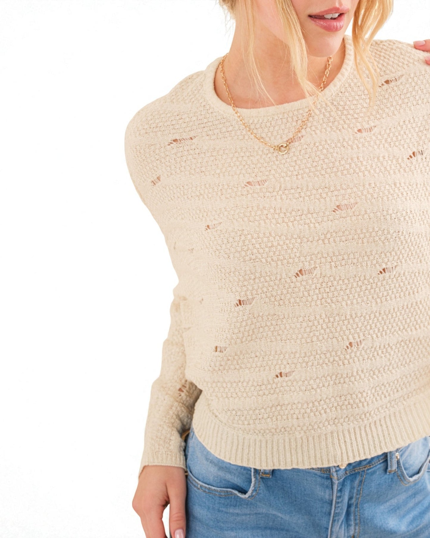 Beige sweater with subtle pattern worn by a person on a white background